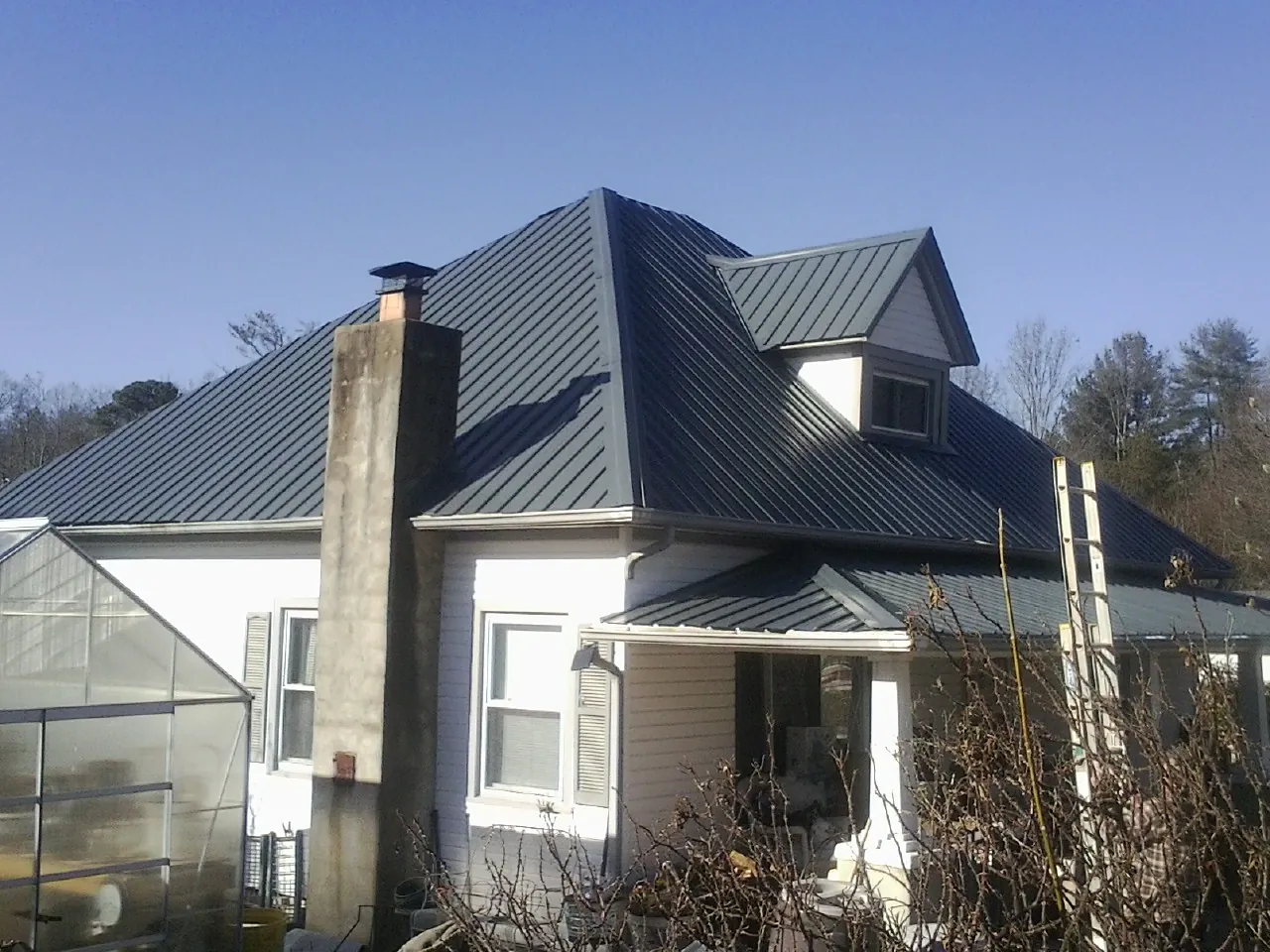 Dark blue standing seam metal roof on a white farmhouse with dormer — Slate & Tile Roof Repair by Roofing Brothers in Mingo Junction