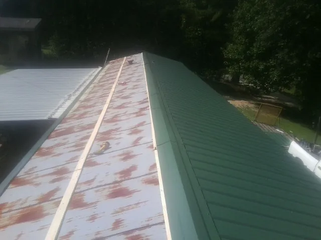 Old rusted panels beside newly installed green metal roofing — Wind Damage Roof Repair by Roofing Brothers in Mingo Junction