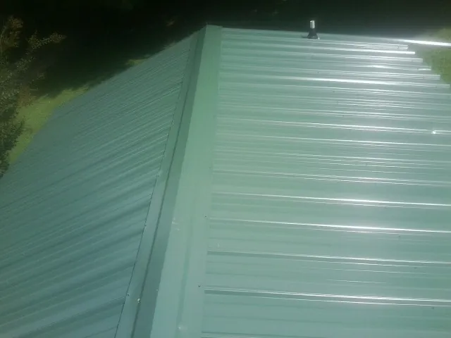 New green metal panels meeting at the ridge of a roof — Flat Roof Repair work by our crew in Mingo Junction
