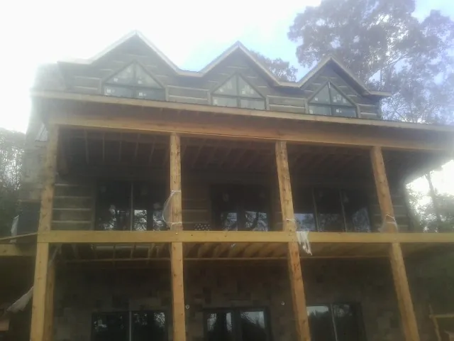 Dormers and porch framing on a large log home under construction — Roof Coating work by our crew in Mingo Junction