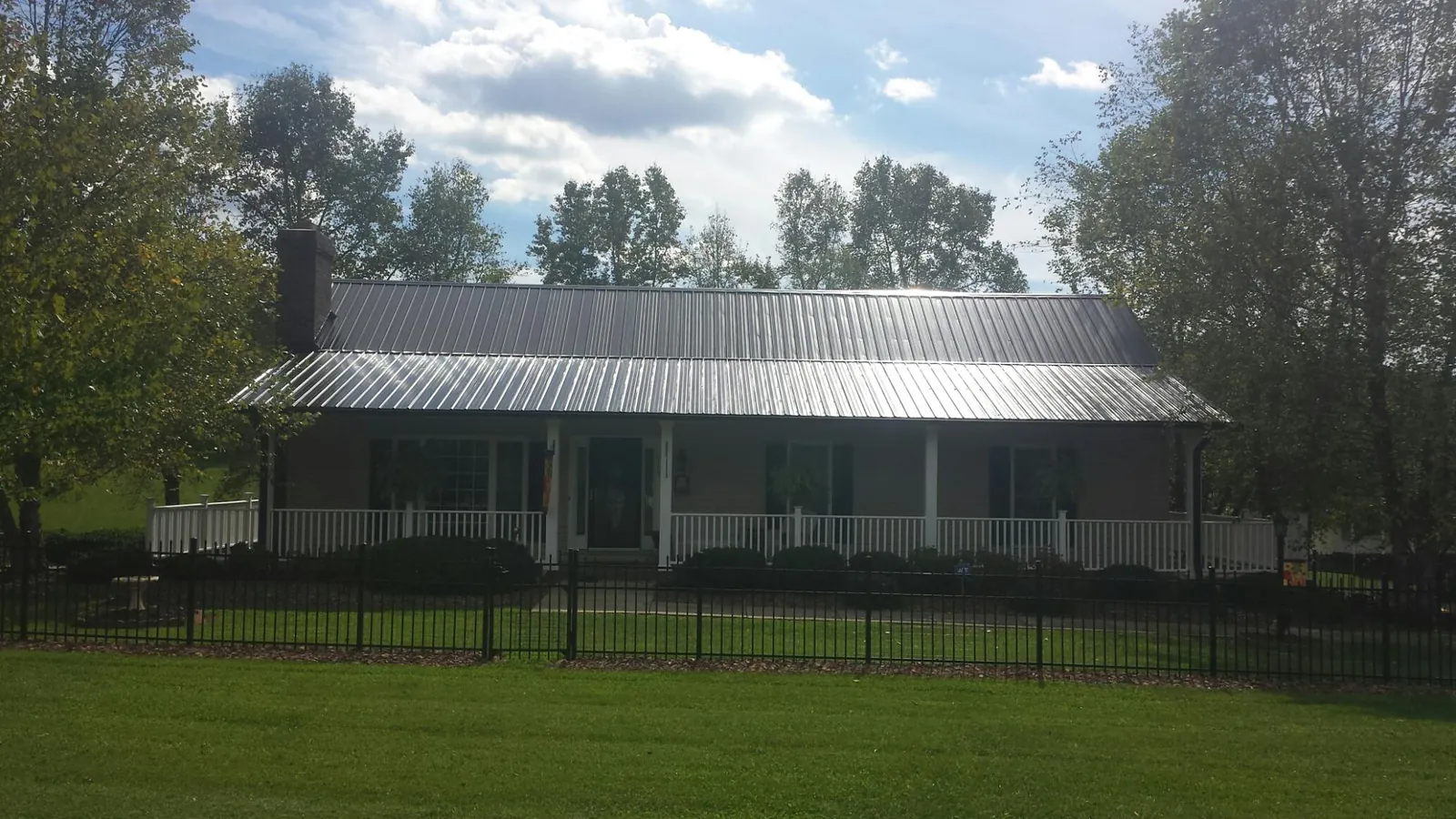 Gray metal roof on a brick ranch with a full width front porch — Gutter Guard Installation work by our crew in Mingo Junction