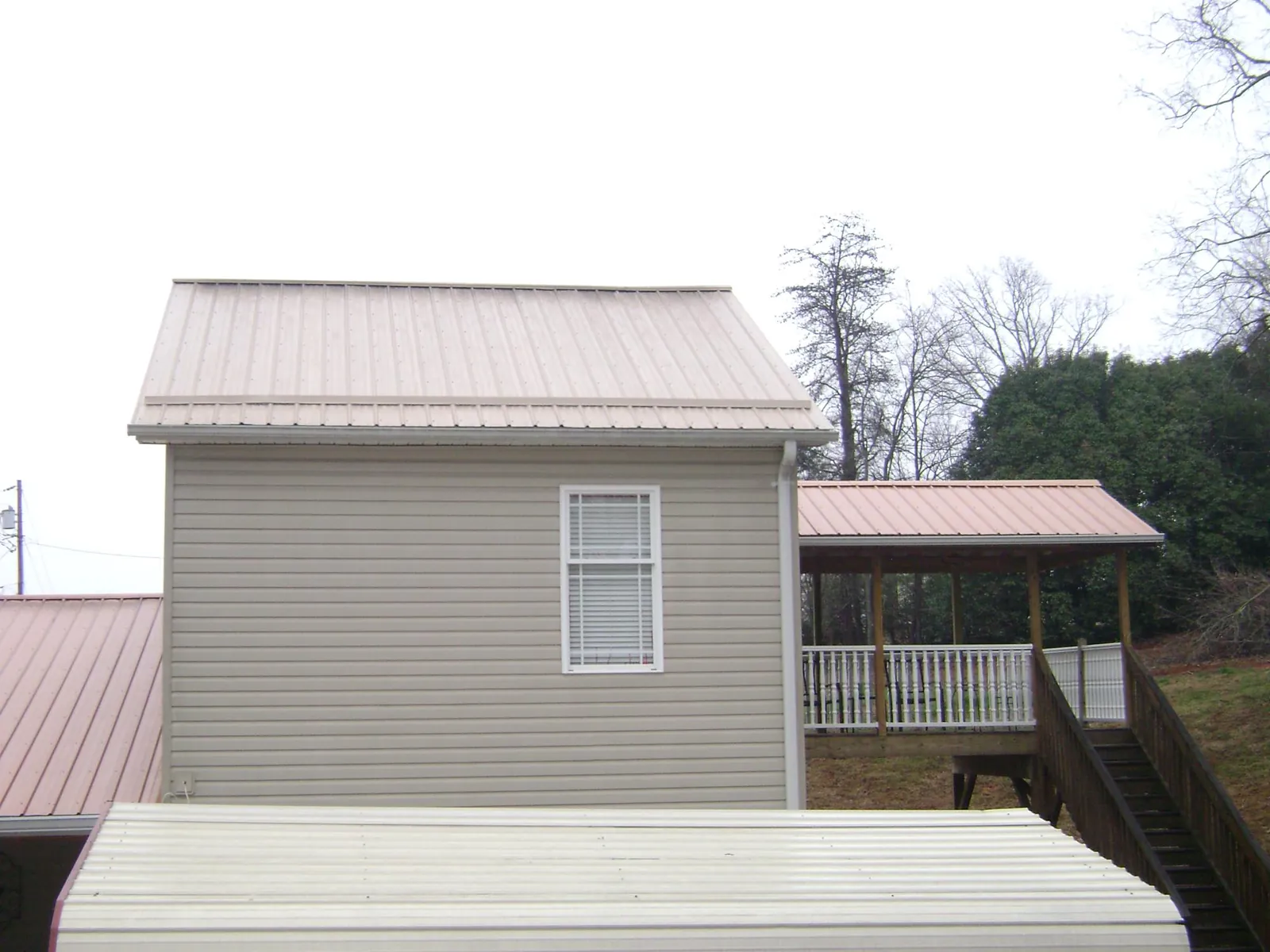 Tan metal roofs on a two story addition and attached porch, from a Roof Replacement job in Mingo Junction